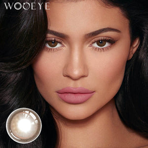The girl's face is looking straight ahead, the upper left is the Wooeye logo, and the lower left is a close-up of the Glossy Brown contact lens