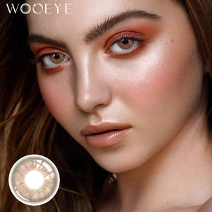 The girl's face is looking straight ahead, the upper left is the Wooeye logo, and the lower left is a close-up of the Coral Grey contact lens