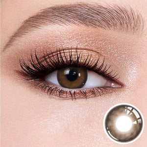 The effect of wearing Mystery Tea Brown Contact Lenses, with a close-up of the product in the lower right corner