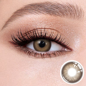 The effect of wearing Aura Brown Contact Lenses, with a close-up of the product in the lower right corner