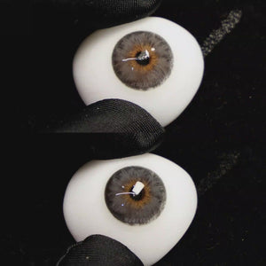 A simulated brown prosthetic eye showing the visual transformation effect of wearing Wooeye Mermaid Grey colored contact lenses against a black background.