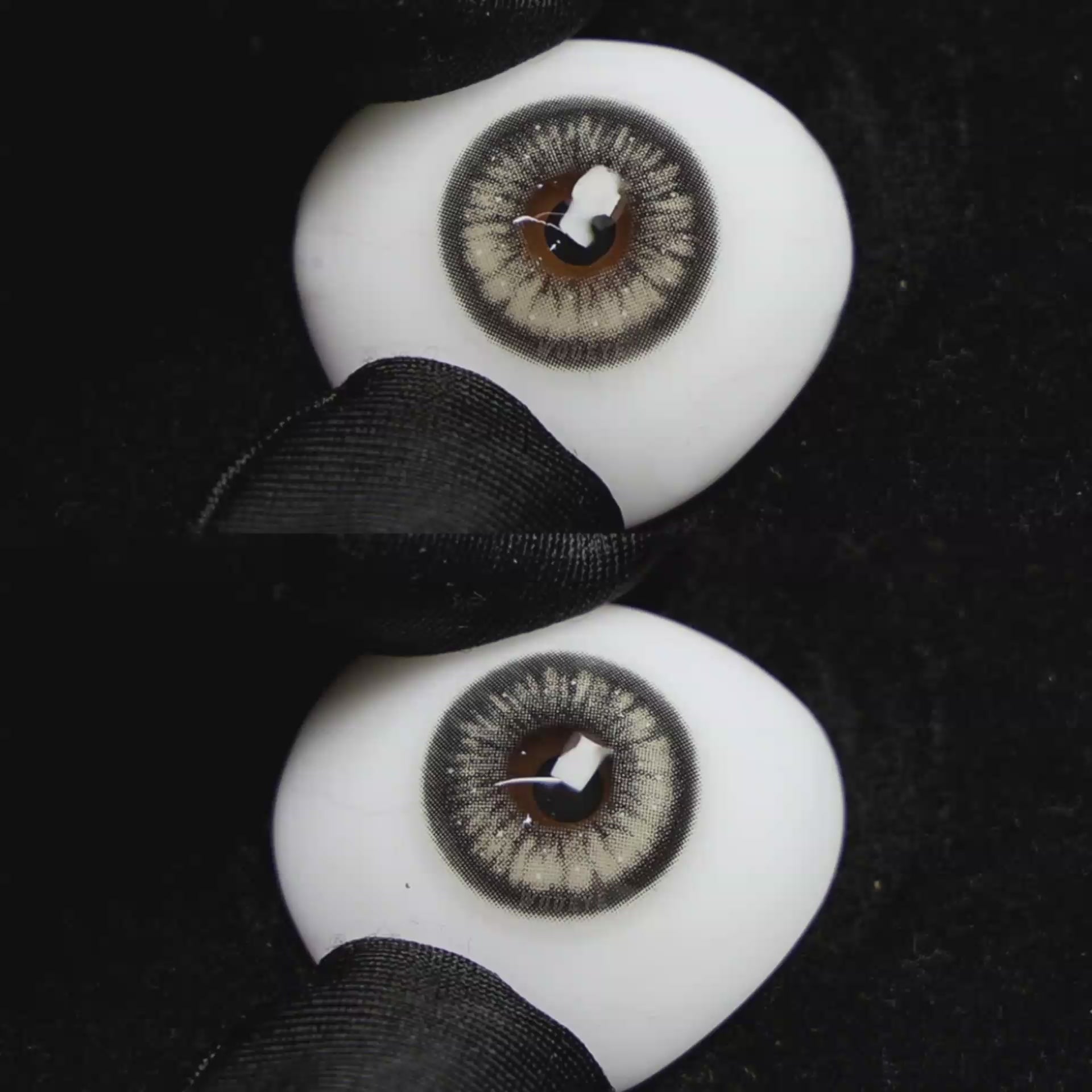A simulated brown prosthetic eye showing the visual transformation effect of wearing Wooeye Jennie Grey I colored contact lenses against a black background.