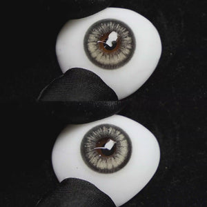 A simulated brown prosthetic eye showing the visual transformation effect of wearing Wooeye Jennie Grey I colored contact lenses against a black background.