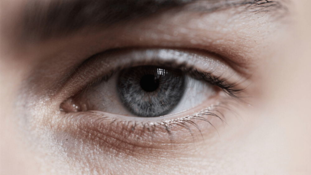 Close-up of a dark gray human eye showing natural beauty, clarity, and calm expression.