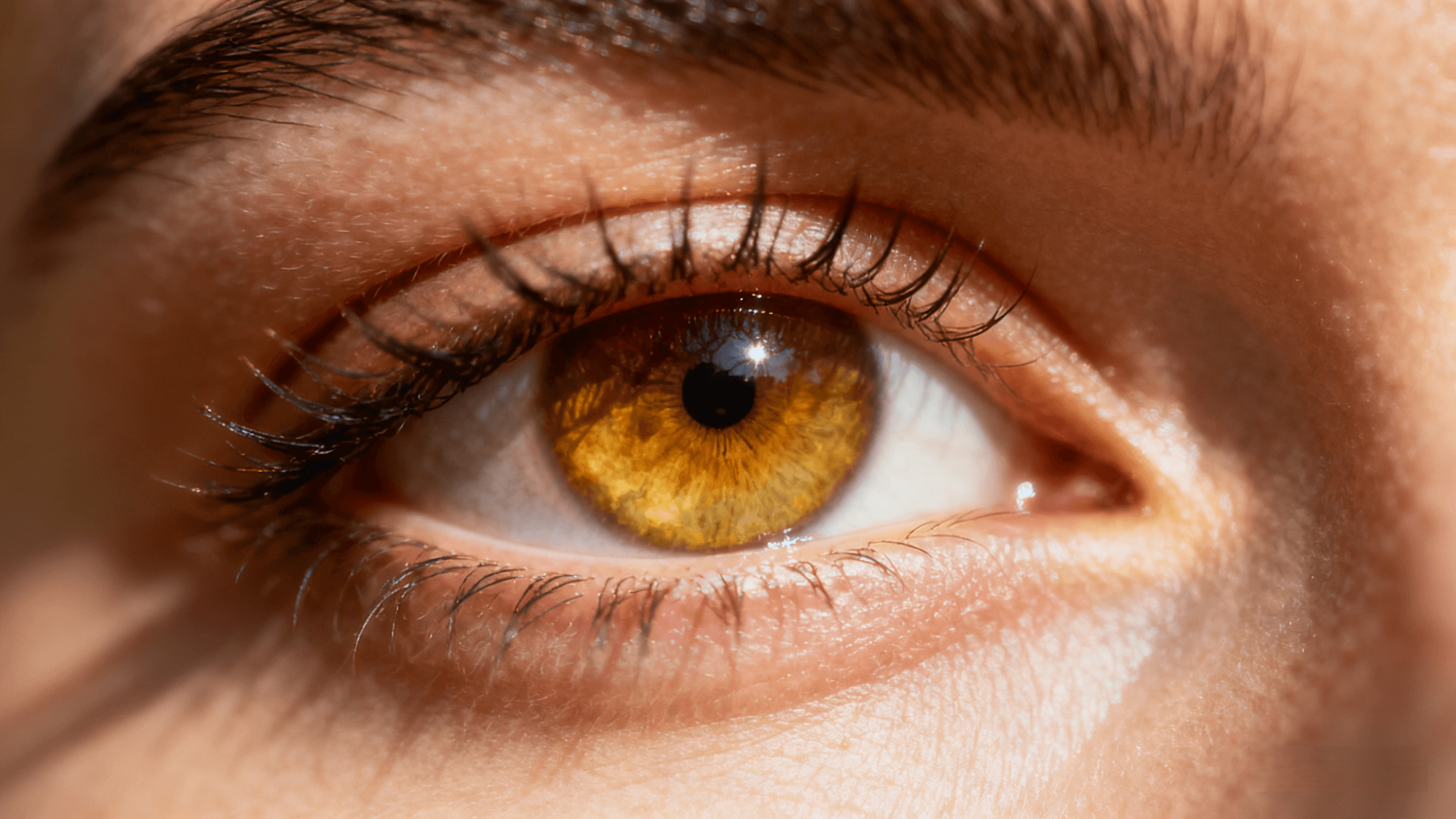 Close-up of a bright amber human eye showing natural beauty, clarity, and calm expression.