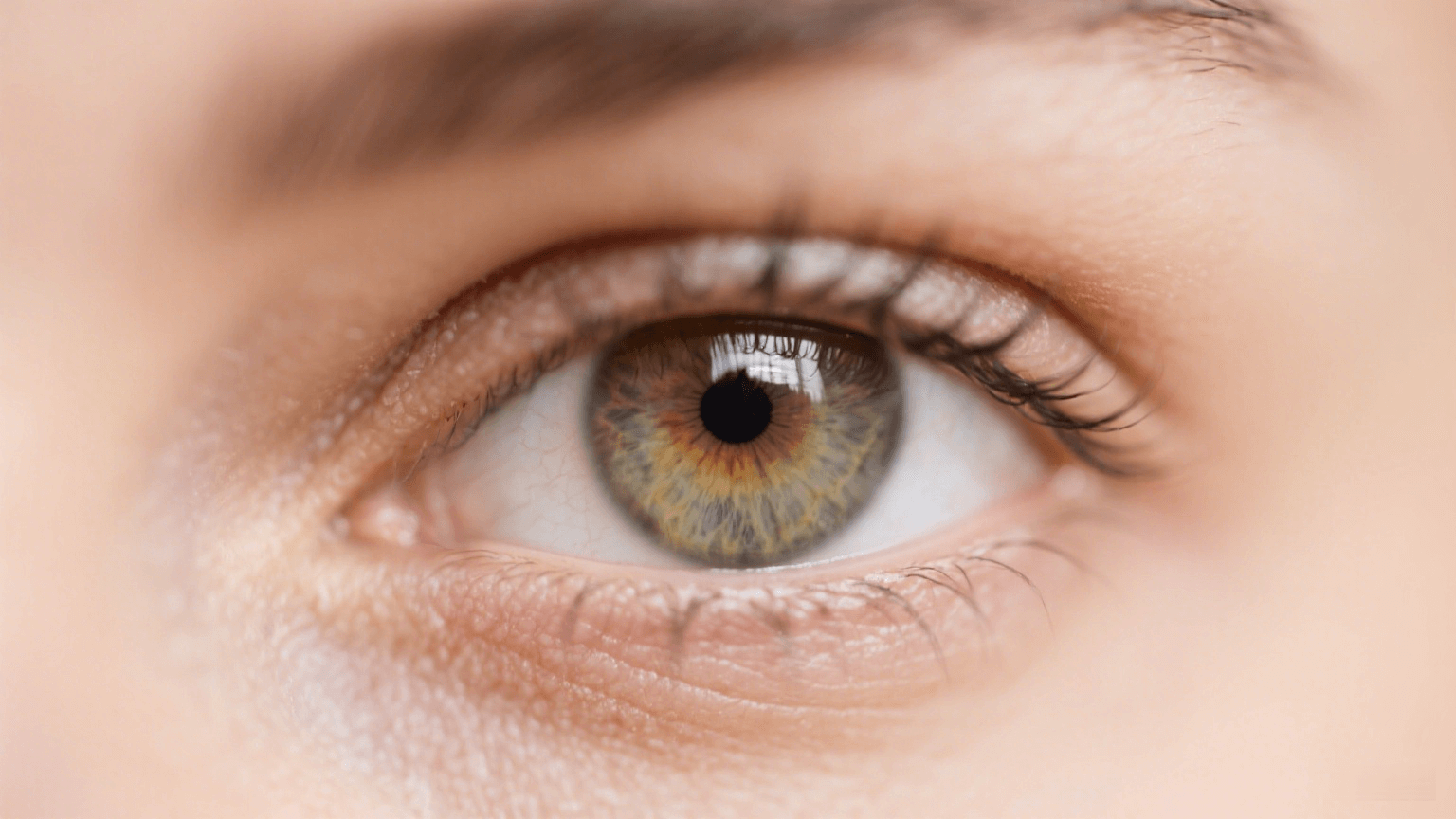 Close-up of a light hazel eye with intricate iris details and long eyelashes.