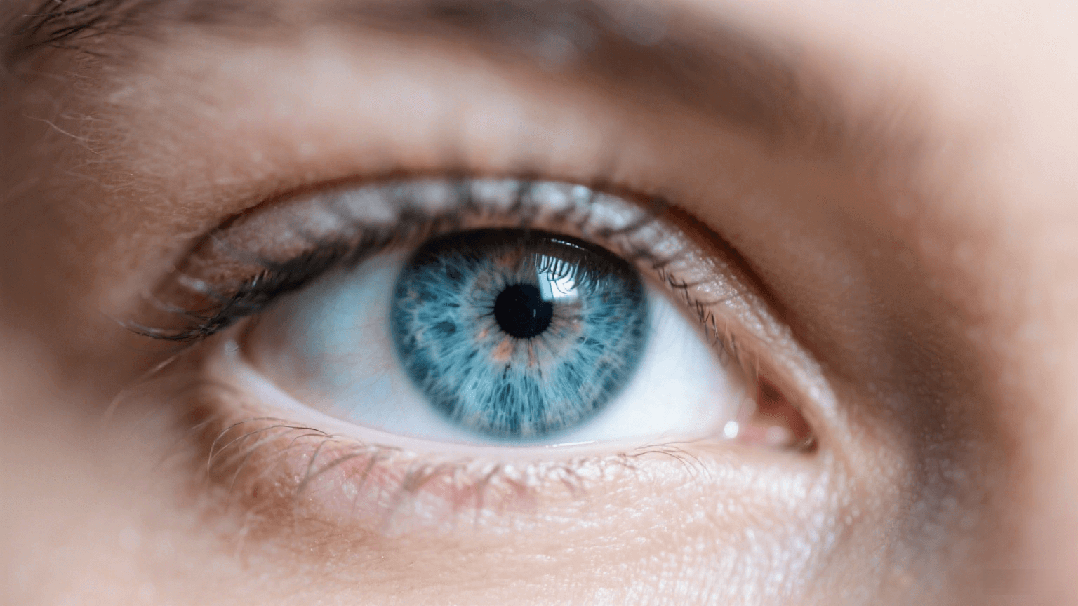 Close-up of a blue hazel eye with intricate iris details and long eyelashes.