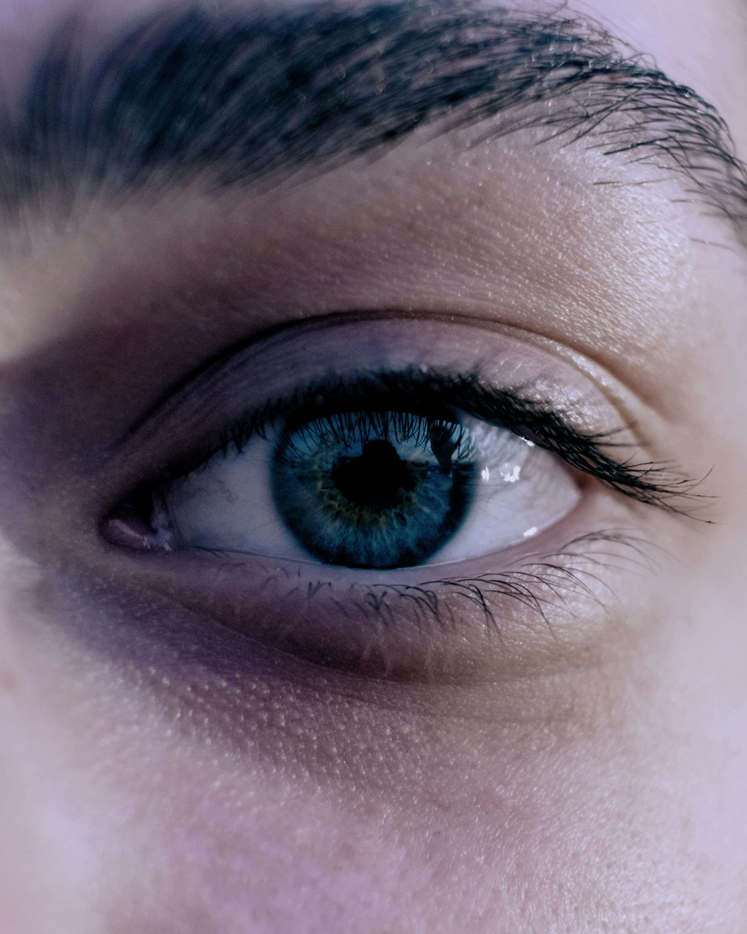Close-up of a dark blue human eye showing natural beauty, clarity, and calm expression.