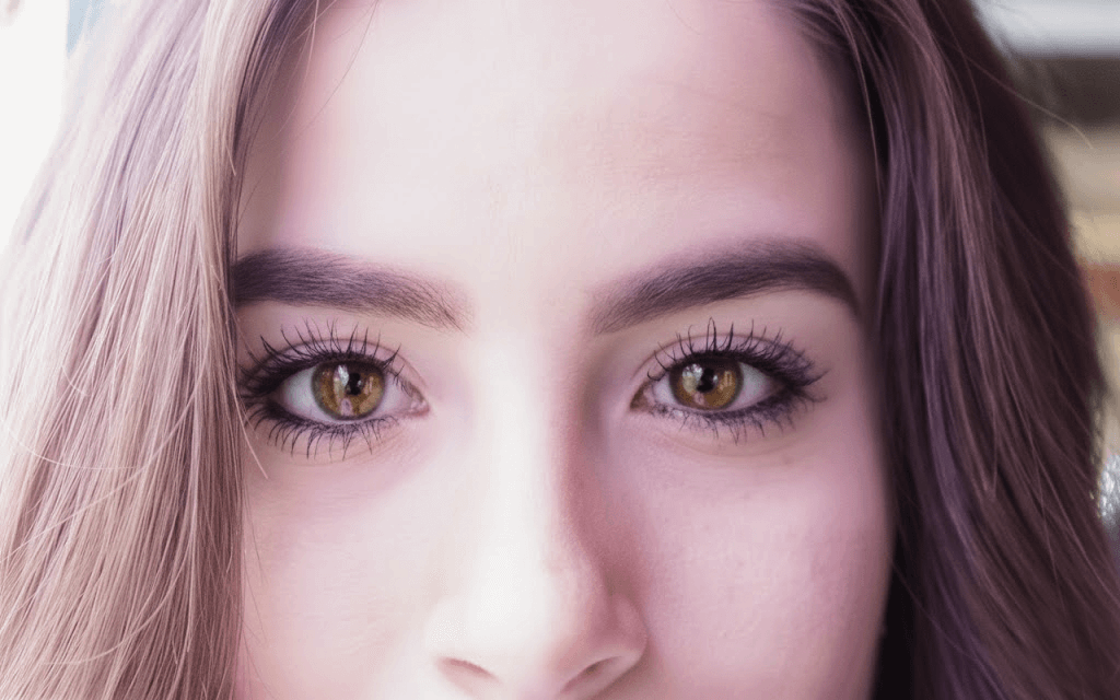 Close-up of a young person’s face with bright hazel eyes and long eyelashes. 