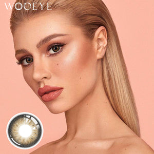 The girl's face is looking straight ahead, the upper left is the Wooeye logo, and the lower left is a close-up of the Acorn Lily Grey contact lens
