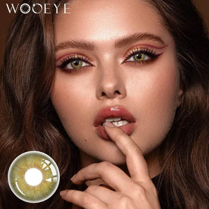 The girl's face is looking straight ahead, the upper left is the Wooeye logo, and the lower left is a close-up of the Origin Glow Hazel Brown contact lens