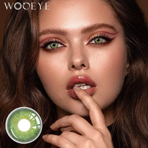 The girl's face is looking straight ahead, the upper left is the Wooeye logo, and the lower left is a close-up of the Origin Glow Green contact lens