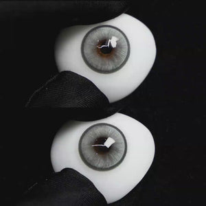 A simulated brown prosthetic eye showing the visual transformation effect of wearing Wooeye Boston Grey colored contact lenses against a black background.