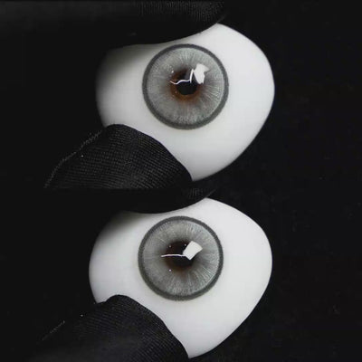 A simulated brown prosthetic eye showing the visual transformation effect of wearing Wooeye Boston Grey colored contact lenses against a black background.