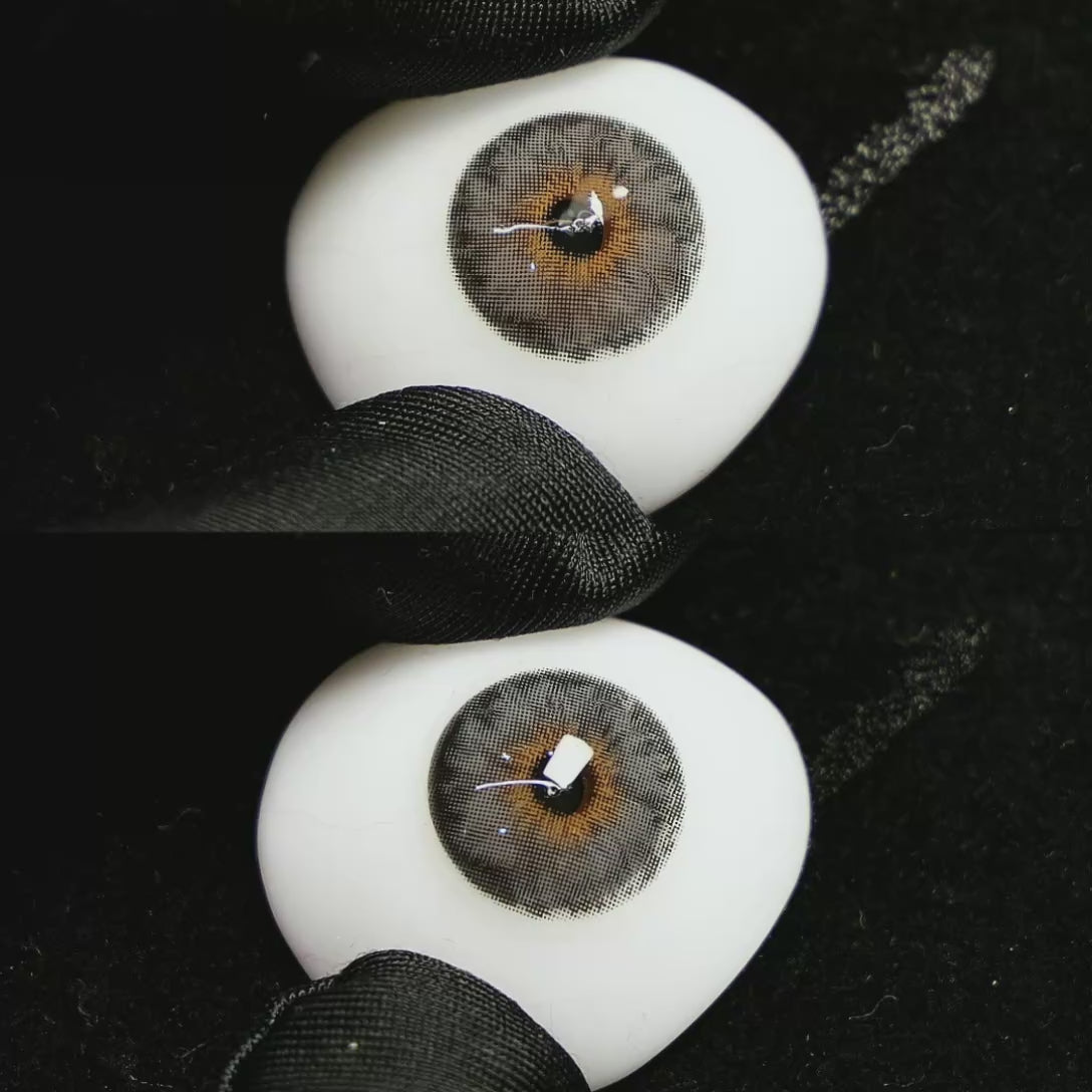 A simulated brown prosthetic eye showing the visual transformation effect of wearing Mermaid Grey colored contact lenses against a black background.