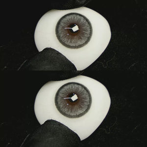 A simulated brown prosthetic eye showing the visual transformation effect of wearing Sugar Grey colored contact lenses against a black background.