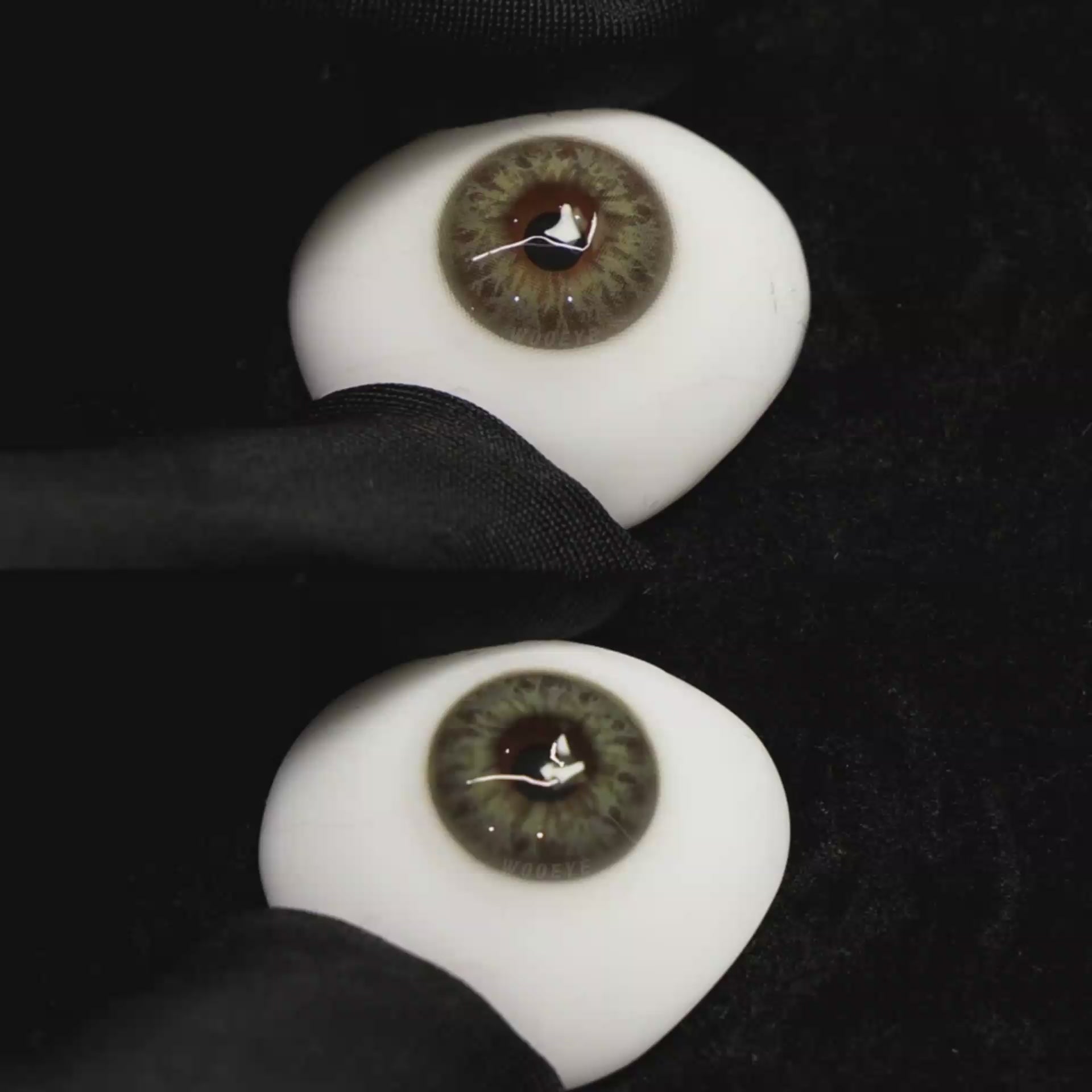 A simulated brown prosthetic eye showing the visual transformation effect of wearing Wooeye Taylor Green colored contact lenses against a black background.