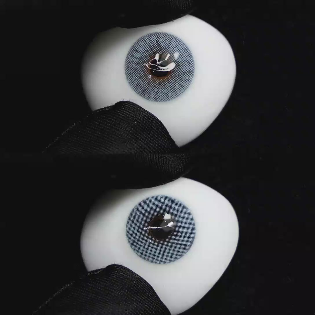 A simulated brown prosthetic eye showing the visual transformation effect of wearing Wooeye Mulberry Blue colored contact lenses against a black background.