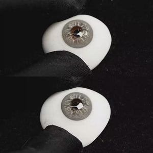A simulated brown prosthetic eye showing the visual transformation effect of wearing Cape Cod Grey colored contact lenses against a black background.