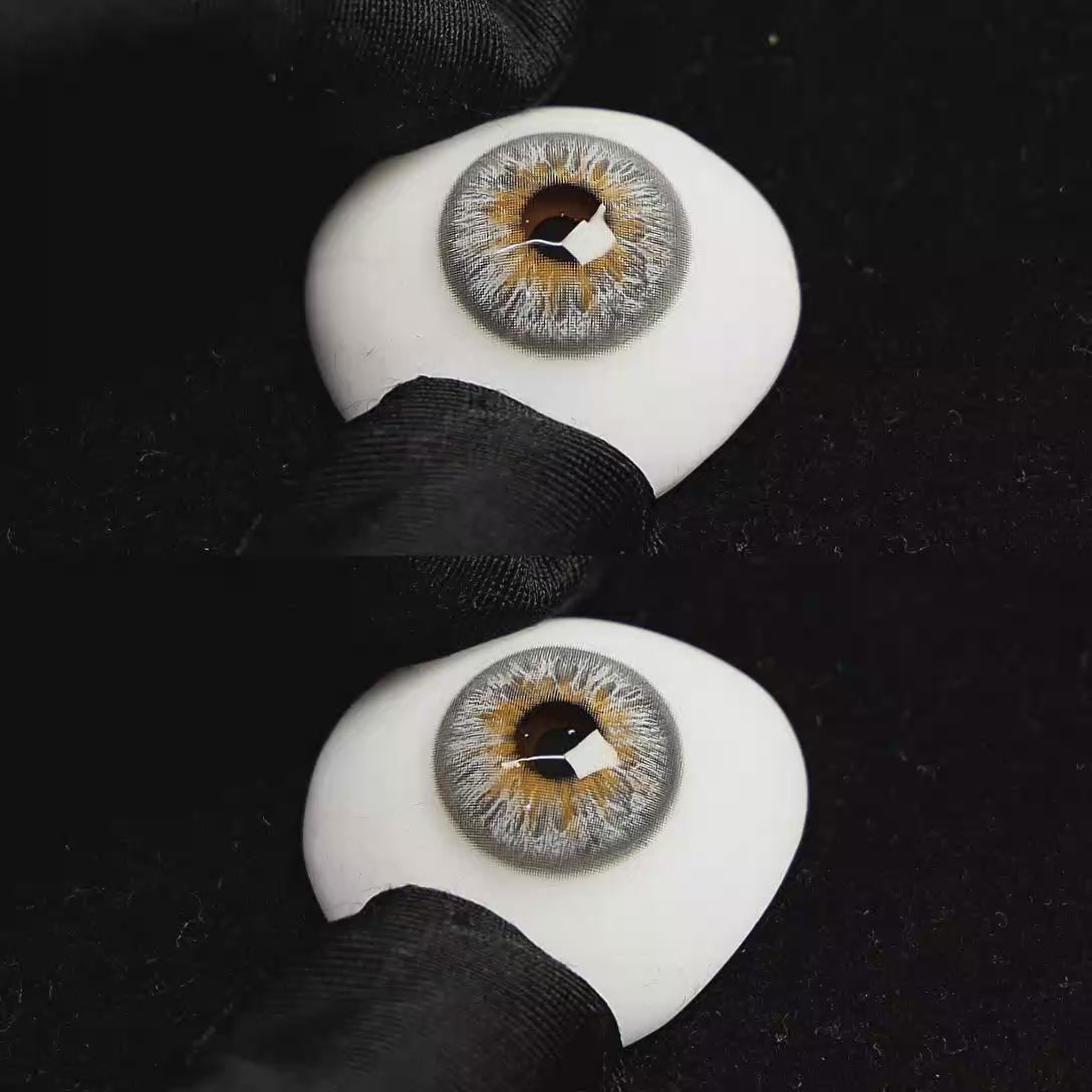 A simulated brown prosthetic eye showing the visual transformation effect of wearing Vegas Grey colored contact lenses against a black background.