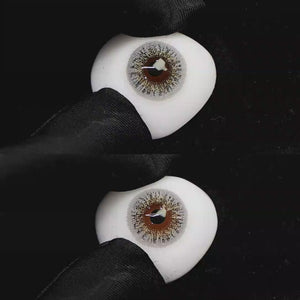 A simulated brown prosthetic eye showing the visual transformation effect of wearing Wooeye Freedom Gray I colored contact lenses against a black background.