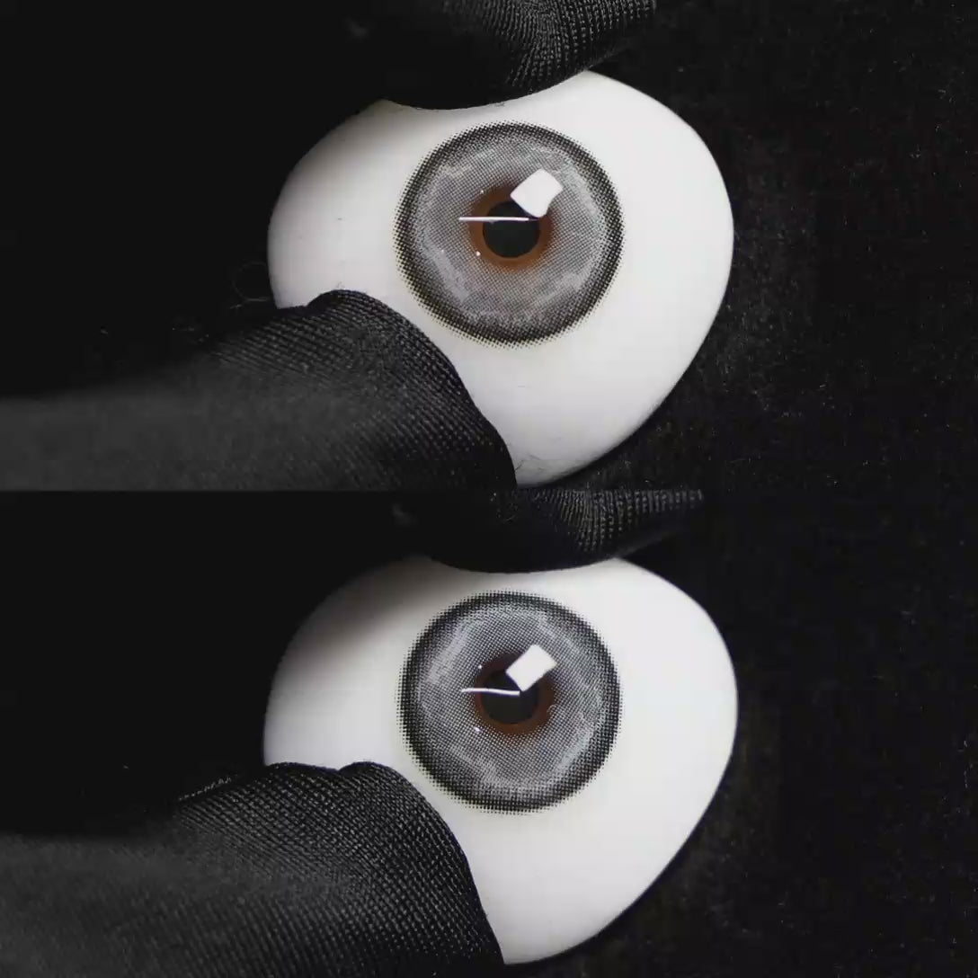 A simulated brown prosthetic eye showing the visual transformation effect of wearing Wooeye Heaven Gray colored contact lenses against a black background.