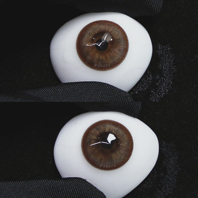 A simulated brown prosthetic eye showing the visual transformation effect of wearing Wooeye Mystery Tea Brown colored contact lenses against a black background.