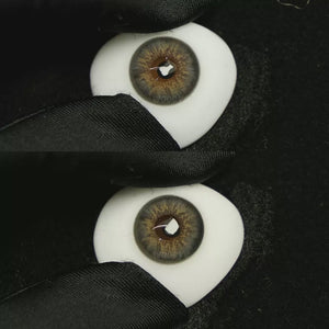 A simulated brown prosthetic eye showing the visual transformation effect of wearing Dancer Deep Grey colored contact lenses against a black background.