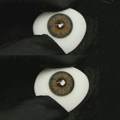 A simulated brown prosthetic eye showing the visual transformation effect of wearing Dancer Deep Grey colored contact lenses against a black background.
