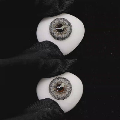 A simulated brown prosthetic eye showing the visual transformation effect of wearing Wooeye Galaxy Gray I colored contact lenses against a black background.
