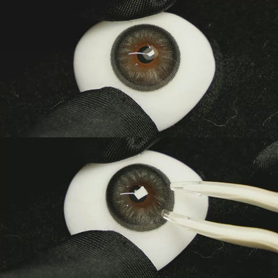 A simulated brown prosthetic eye showing the visual transformation effect of wearing Acorn Amber Grey colored contact lenses against a black background.