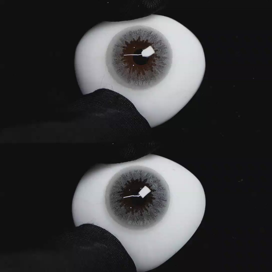 A simulated brown prosthetic eye showing the visual transformation effect of wearing Wooeye Queen Gray colored contact lenses against a black background.