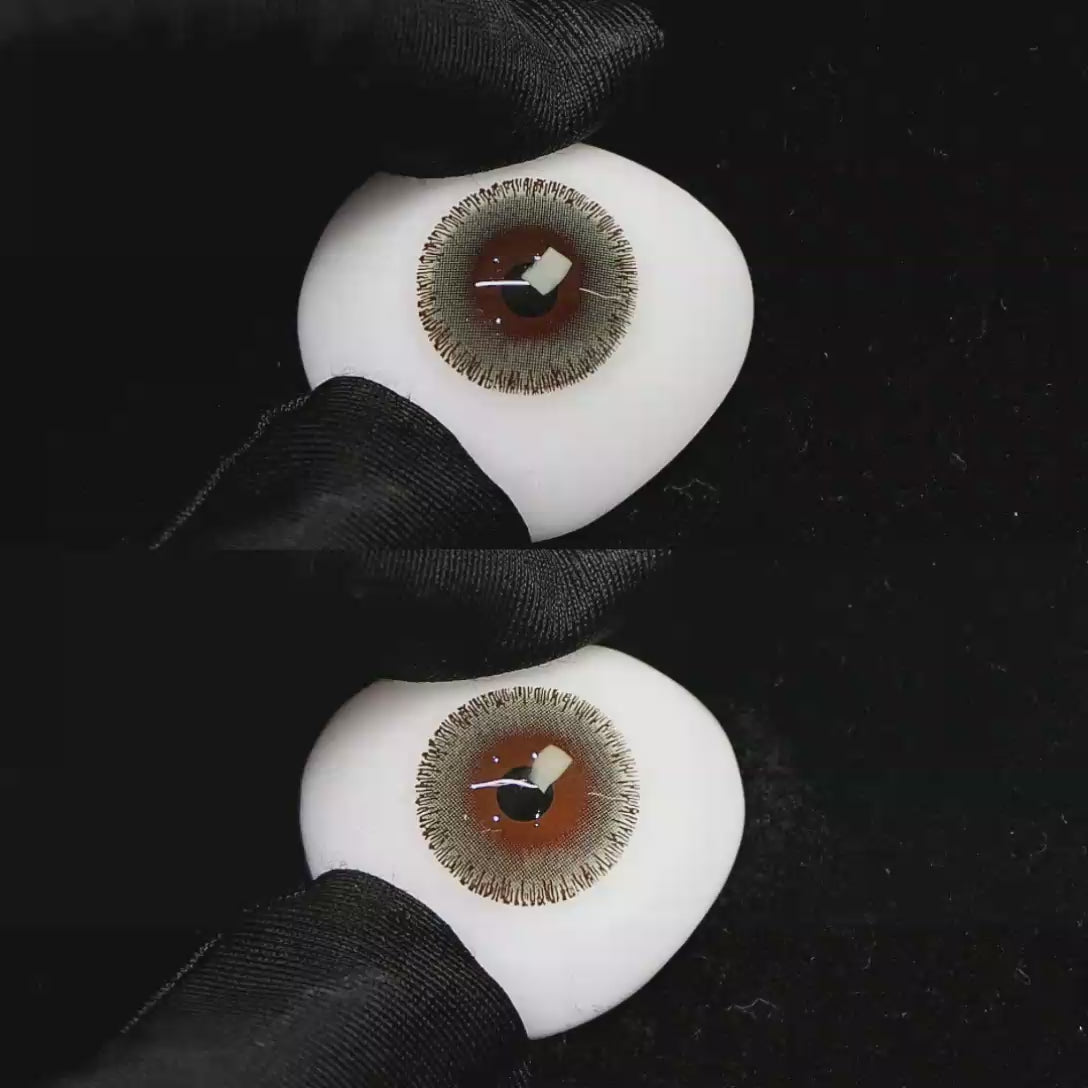 A simulated brown prosthetic eye showing the visual transformation effect of wearing Wooeye Cream Oat Gray colored contact lenses against a black background.
