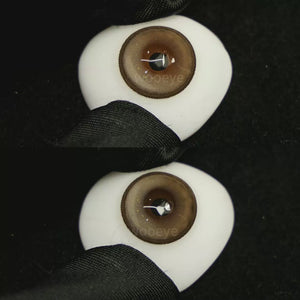 A simulated brown prosthetic eye showing the visual transformation effect of wearing Milk Grey colored contact lenses against a black background.