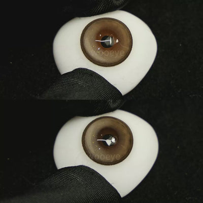 A simulated brown prosthetic eye showing the visual transformation effect of wearing Milk Grey colored contact lenses against a black background.