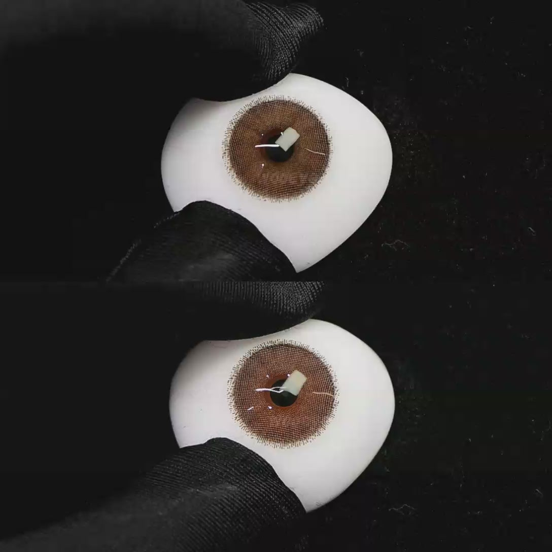 A simulated brown prosthetic eye showing the visual transformation effect of wearing Wooeye Cream Brown II colored contact lenses against a black background.