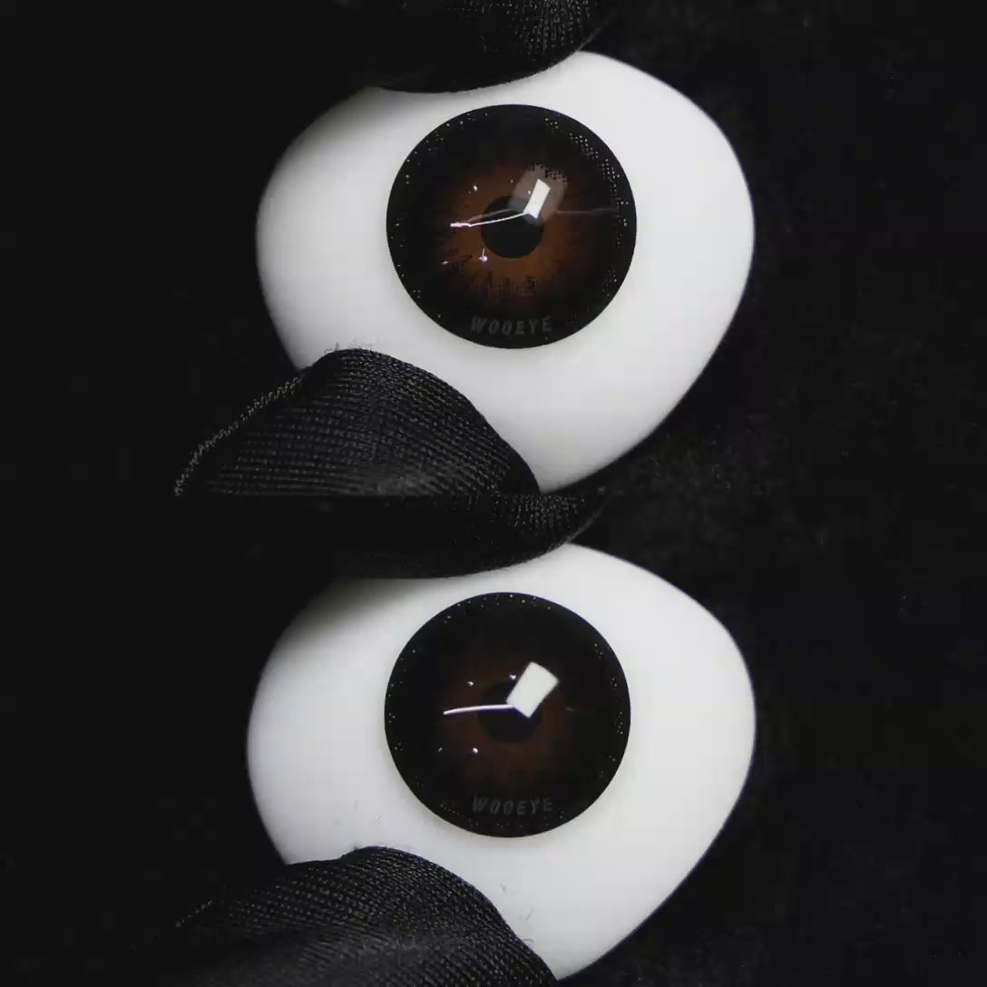 A simulated brown prosthetic eye showing the visual transformation effect of wearing Wooeye Pearl Black colored contact lenses against a black background.