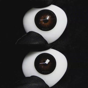 A simulated brown prosthetic eye showing the visual transformation effect of wearing Wooeye Pearl Black colored contact lenses against a black background.