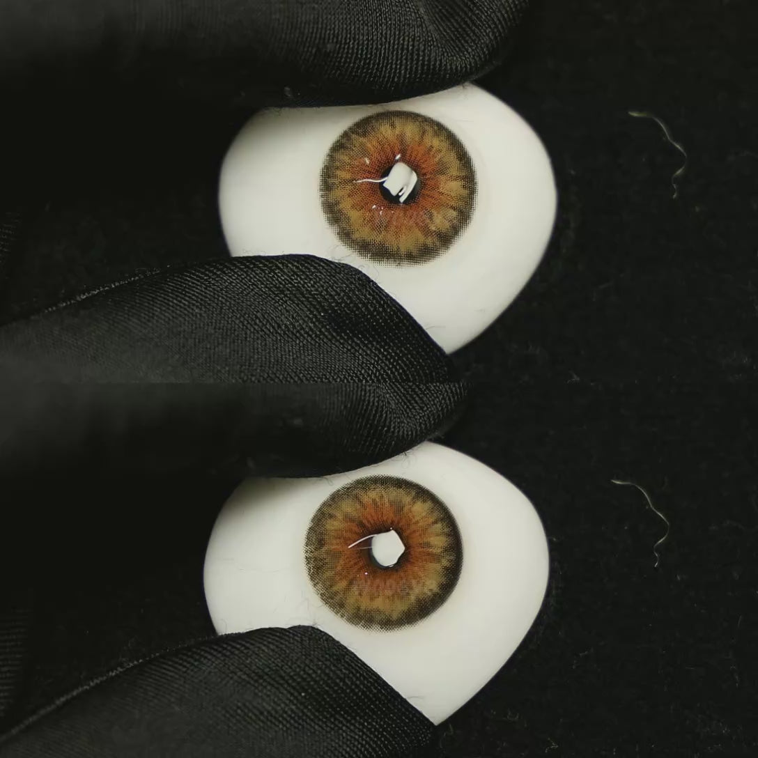 A simulated brown prosthetic eye showing the visual transformation effect of wearing Chamer Brown colored contact lenses against a black background.