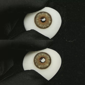 A simulated brown prosthetic eye showing the visual transformation effect of wearing Space Brown colored contact lenses against a black background.