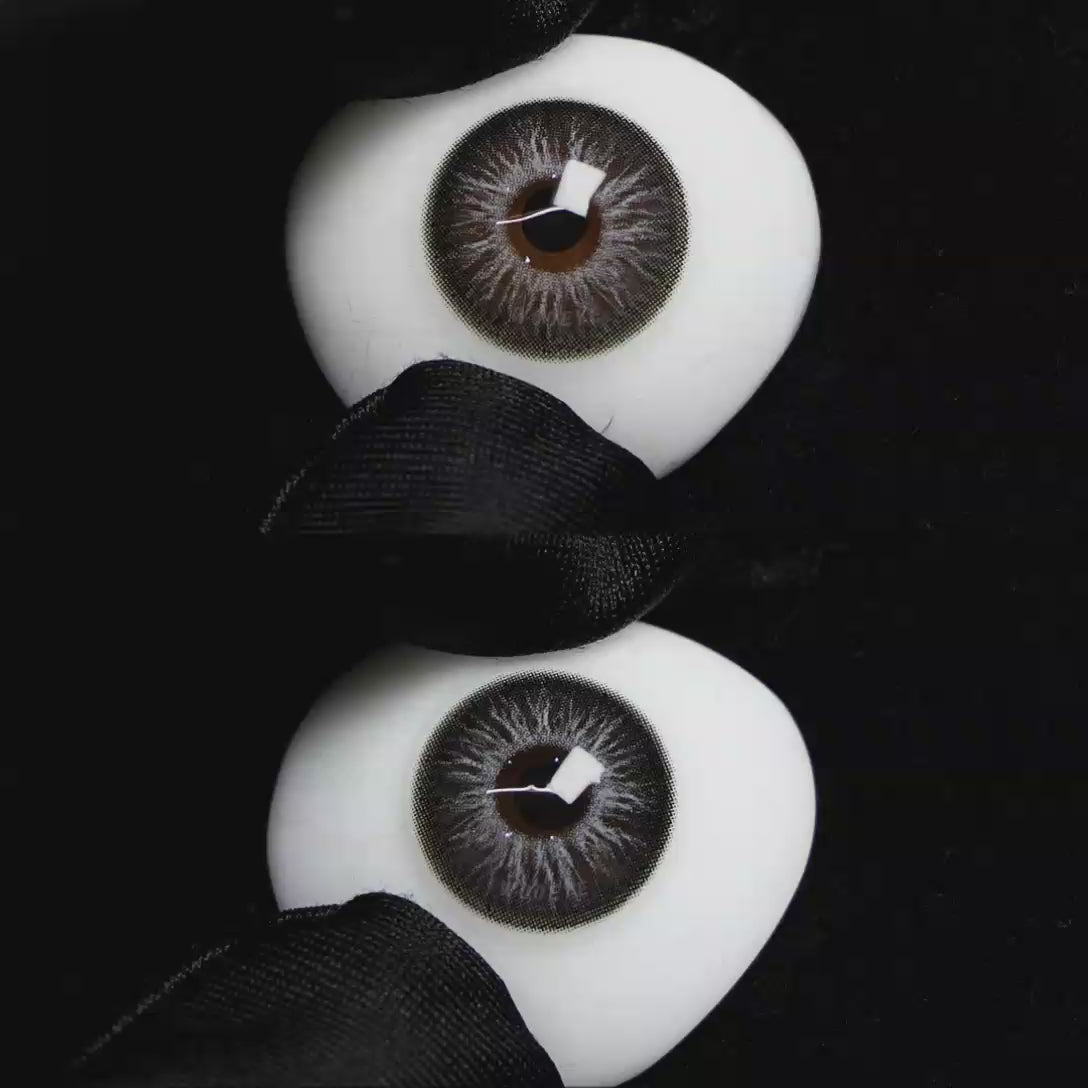 A simulated brown prosthetic eye showing the visual transformation effect of wearing Wooeye Elf Gray colored contact lenses against a black background.