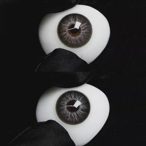 A simulated brown prosthetic eye showing the visual transformation effect of wearing Wooeye Elf Gray colored contact lenses against a black background.