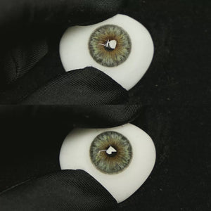 A simulated brown prosthetic eye showing the visual transformation effect of wearing Chamer Grey colored contact lenses against a black background.