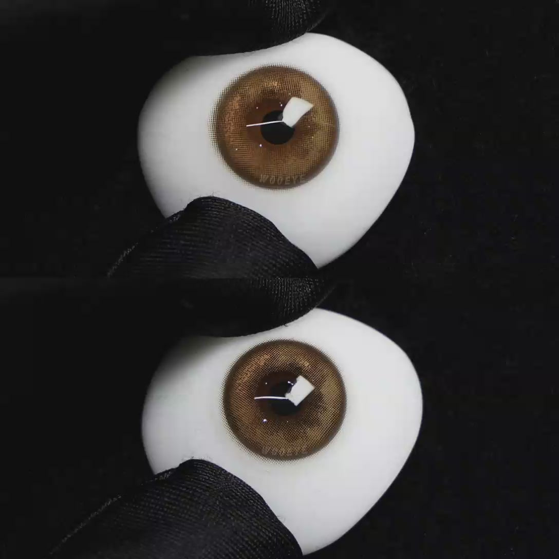 A simulated brown prosthetic eye showing the visual transformation effect of wearing Wooeye Mulberry Brown colored contact lenses against a black background.